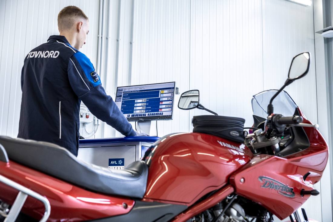 Prüfer misst die Abgaswerte an einem Motorrad