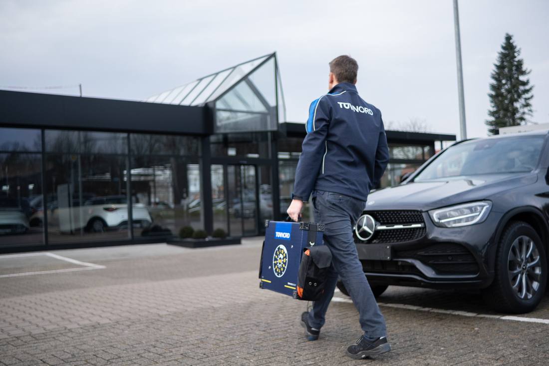 Prüfer trägt den Prüfkoffer zu einem Fahrzeug